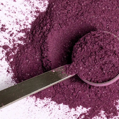 Fioletowy proszek do latte z ube w metalowej miarce na jasnym tle z rozsypanym produktem