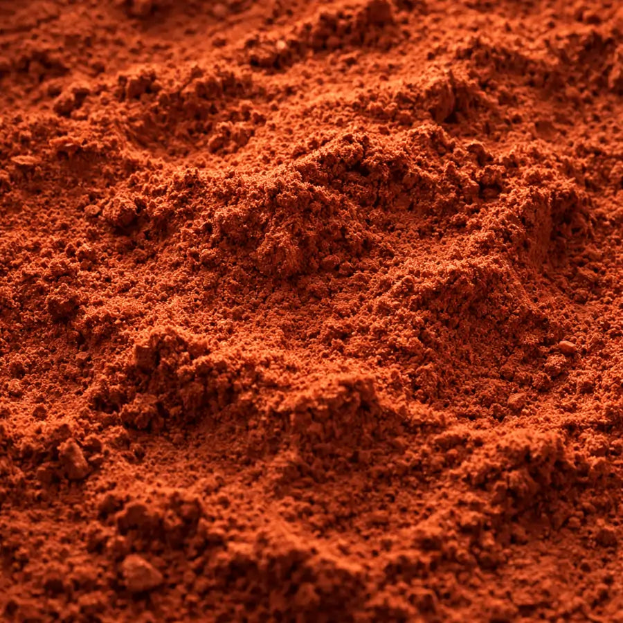 Zbliżenie na proszkowany rooibos – drobno mielona herbata rooibos rozsypana na całym kadrze, intensywnie czerwona struktura