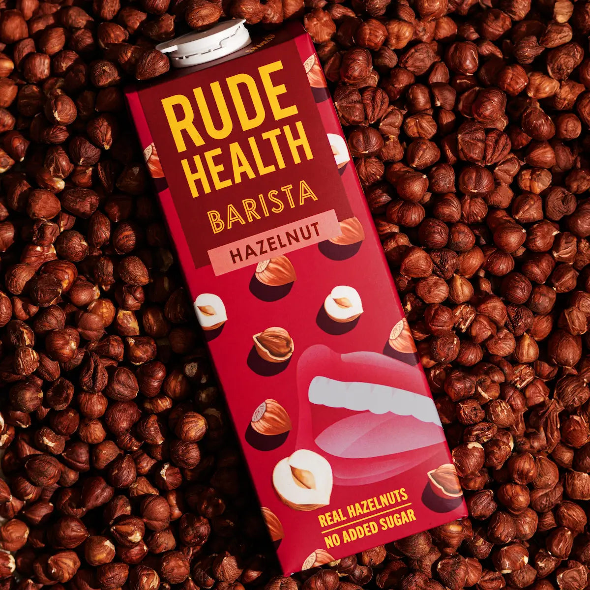 Napój roślinny Rude Health Barista Hazelnut 1L na tle orzechów laskowych, widok z góry, naturalne oświetlenie, intensywne czerwono-brązowe barwy podkreślające smak i skład produktu.