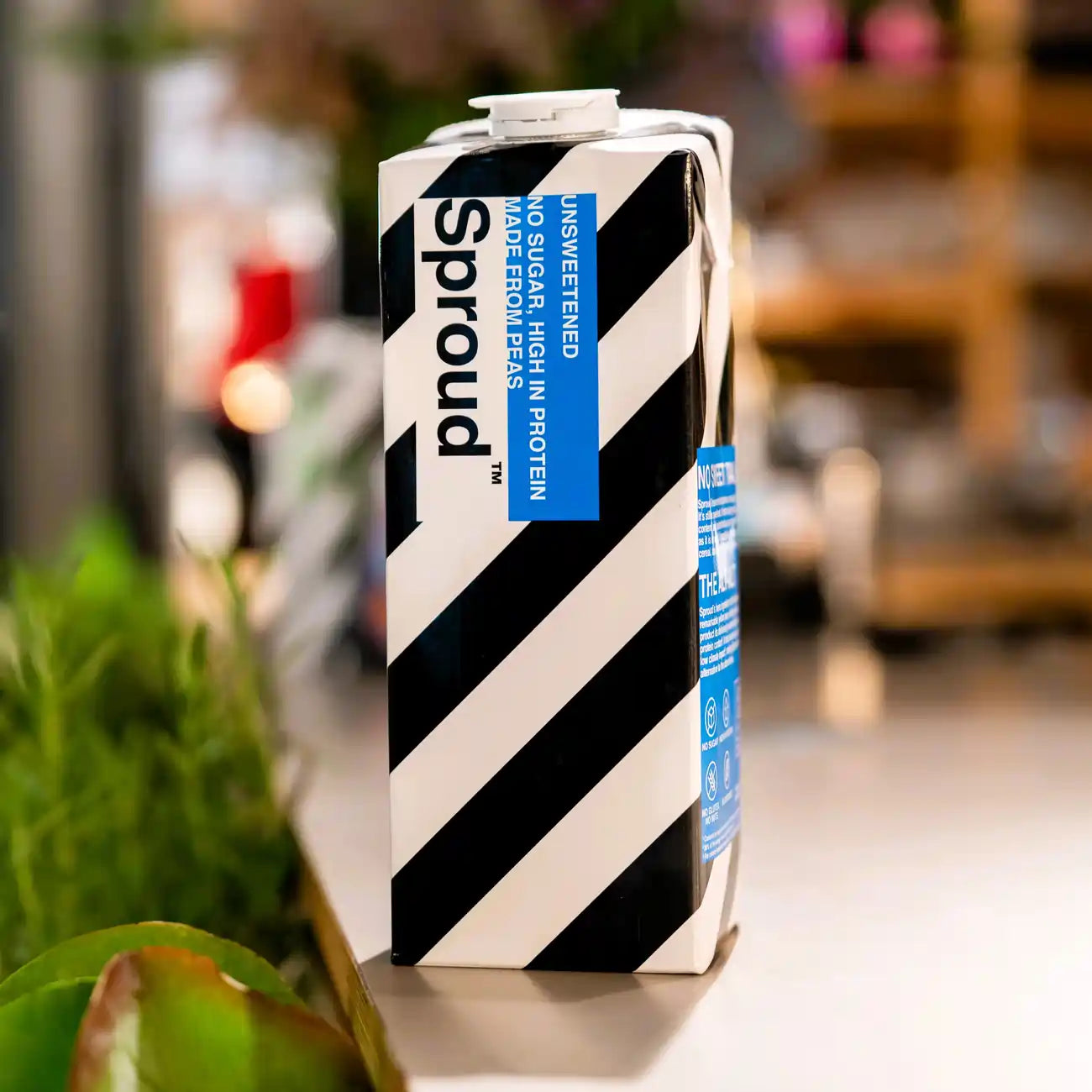 Karton napoju roślinnego Sproud Unsweetened 1L ustawiony na stole – wegański napój z grochu, bez cukru, bogaty w białko, bezglutenowy i bez orzechów.