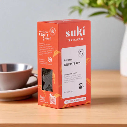 Suki Tea Belfast Brew – czarna herbata liściasta Fairtrade 100g w opakowaniu na stole obok filiżanki