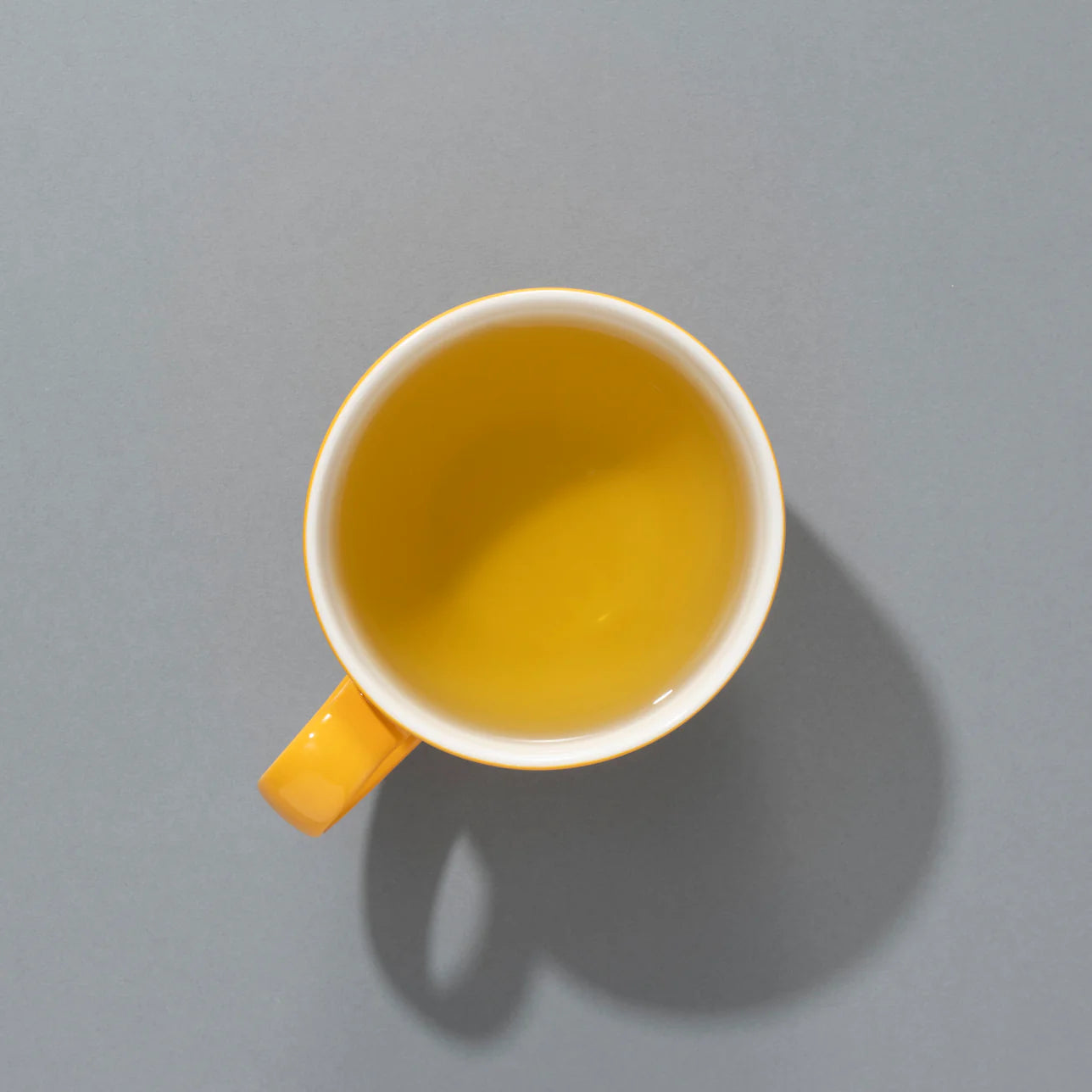 Filiżanka jasnożółtej herbaty Suki SPICED PUMPKIN PIE
 widziana z góry na szarym tle.