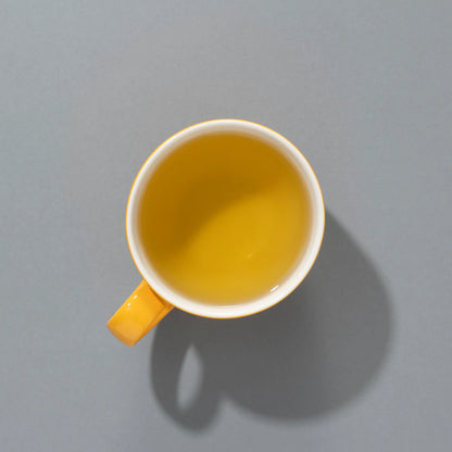 Filiżanka jasnożółtej herbaty Suki SPICED PUMPKIN PIE
 widziana z góry na szarym tle.