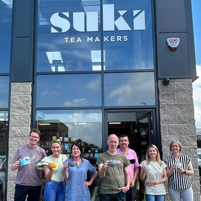 Zespół SUKI Tea Makers przed siedzibą marki, pracownicy trzymają filiżanki herbaty