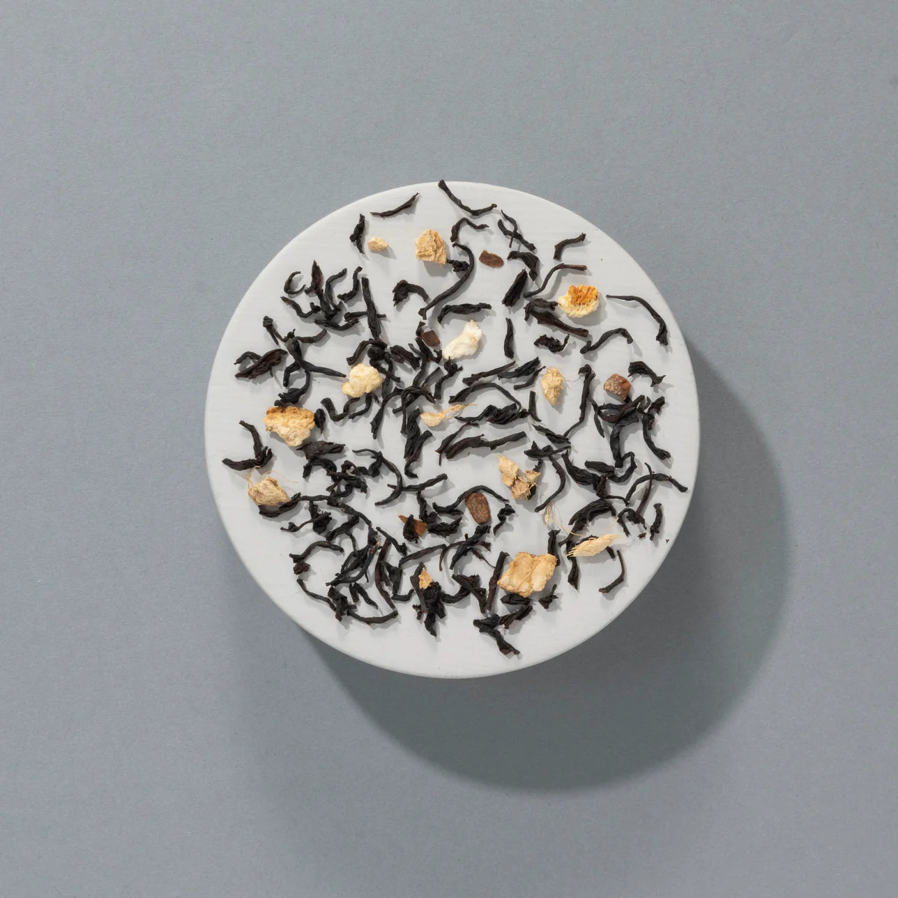 czarna herbata liściasta Suki Tea Mince Pie z widocznymi kawałkami imbiru i przypraw na szarym tle