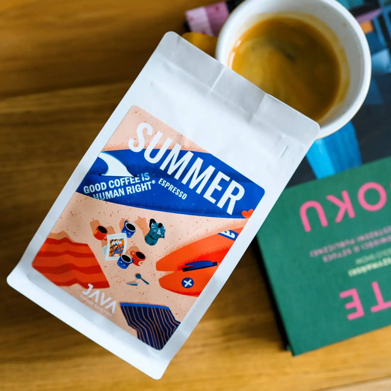 Paczka Summer Espresso od JAVA Coffee Roasters obok filiżanki espresso i książki na drewnianym stoliku, widok z góry