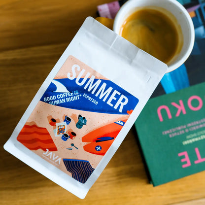 Paczka Summer Espresso od JAVA Coffee Roasters obok filiżanki espresso i książki na drewnianym stoliku, widok z góry