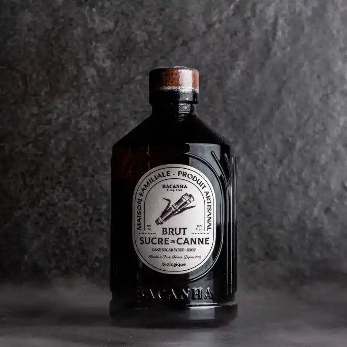 Butelka syropu Bacanha Sucre de Canne Brut – organiczny syrop z cukru trzcinowego na ciemnym tle