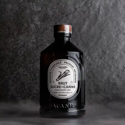 Butelka syropu Bacanha Sucre de Canne Brut – organiczny syrop z cukru trzcinowego na ciemnym tle