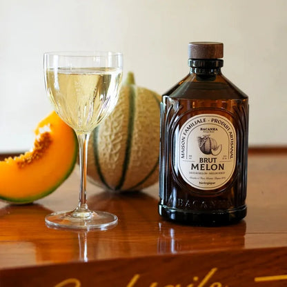 Syrop melonowy Bacanha Brut Melon BIO 400 ml – butelka syropu z kieliszkiem napoju i świeżym melonem, zdjęcie lifestyle