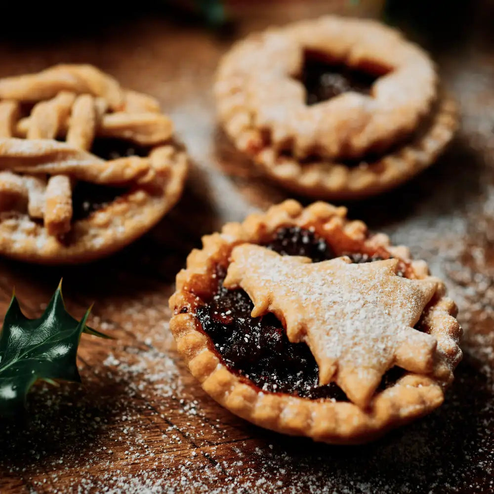 tradycyjne babeczki mince pies z bakaliami i kruchym ciastem, posypane cukrem pudrem na drewnianym tle