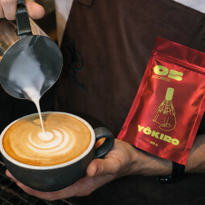 Lifestyle zdjęcie rooibos latte z latte art, przygotowywane przez baristę, z opakowaniem Yōkiro Rooibos 100 g